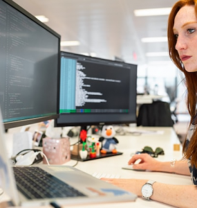 Female software engineer codes at computer