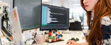 Female software engineer codes at computer