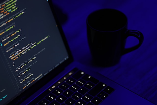 Laptop with code and near cup of coffee