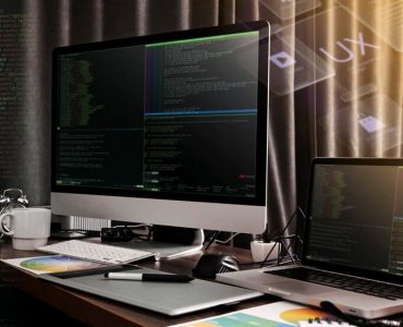 Monitor and a Laptop Against the Backdrop of Code