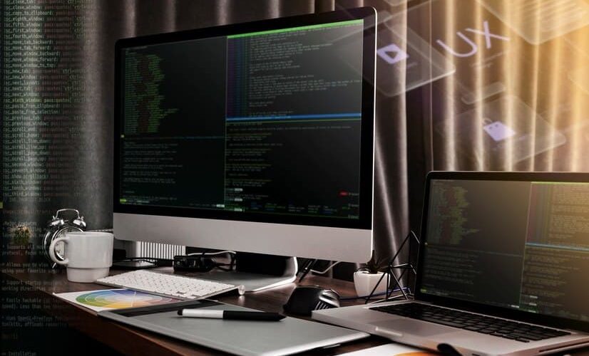 Monitor and a Laptop Against the Backdrop of Code